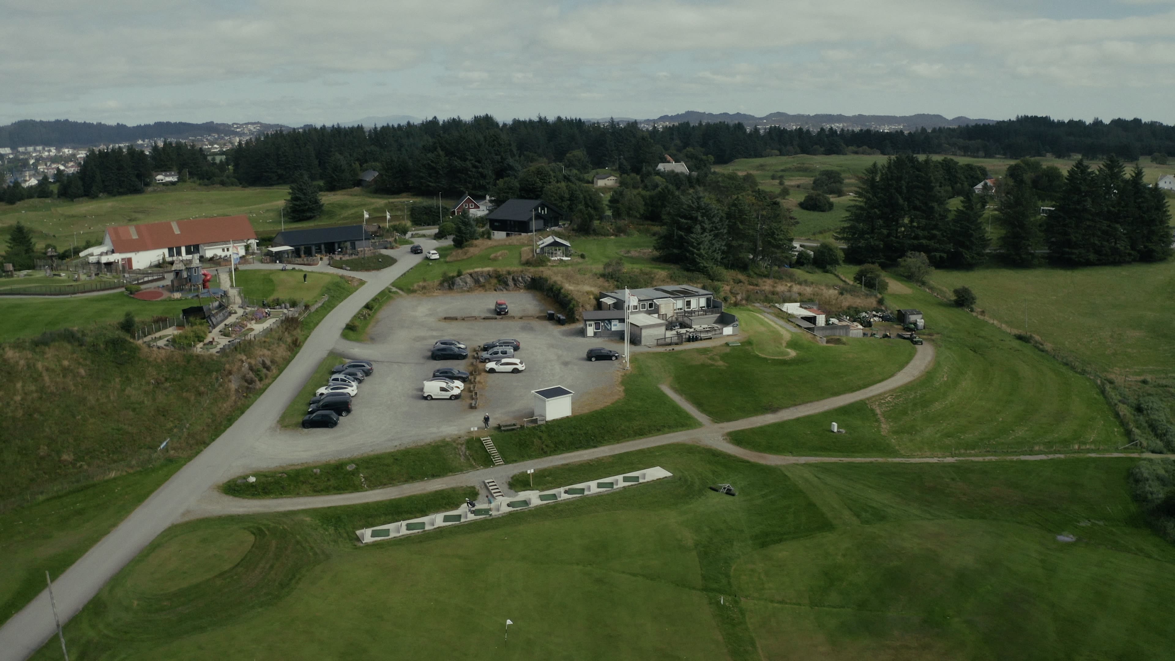 Klubbhuset og anlegget sett ovenfra, med parkering, driving range og banen rundt